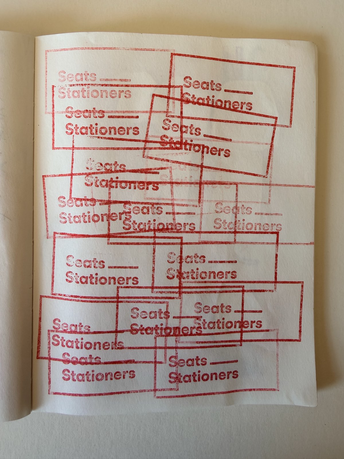 A notebook page covered edge to edge in overlapping red rubber-stamp impressions reading Seats Stationers.